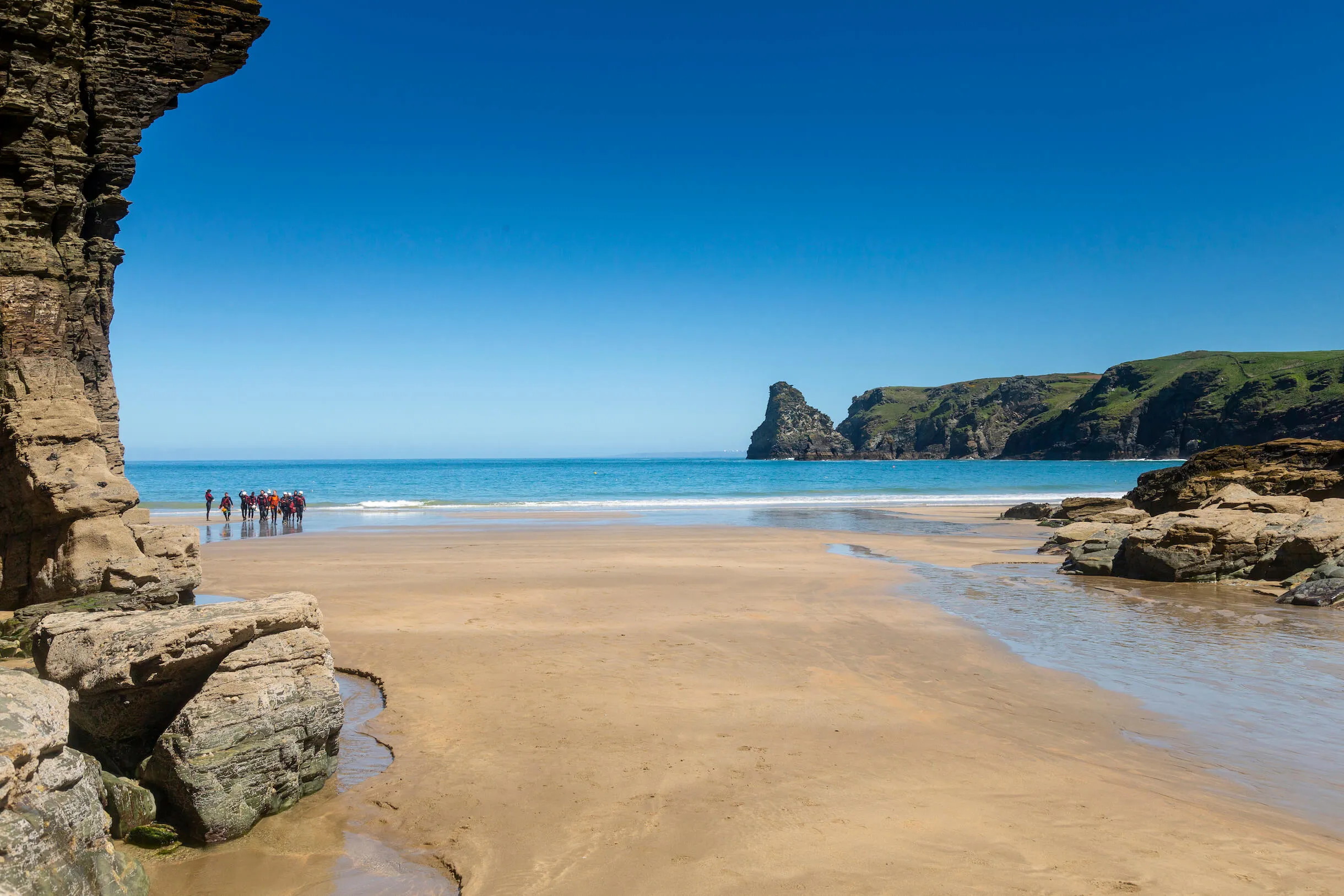 beautiful beach at Bossiney cove with a group of people coming out of the sea with OA Surf Club