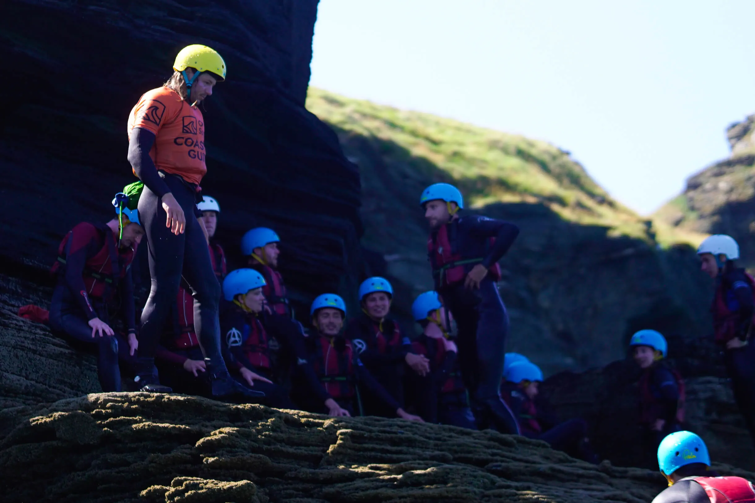 coasteering cornwall - great for corporate events in cornwall. Image of group standing with instructor on rocks, ready to jump in the sea