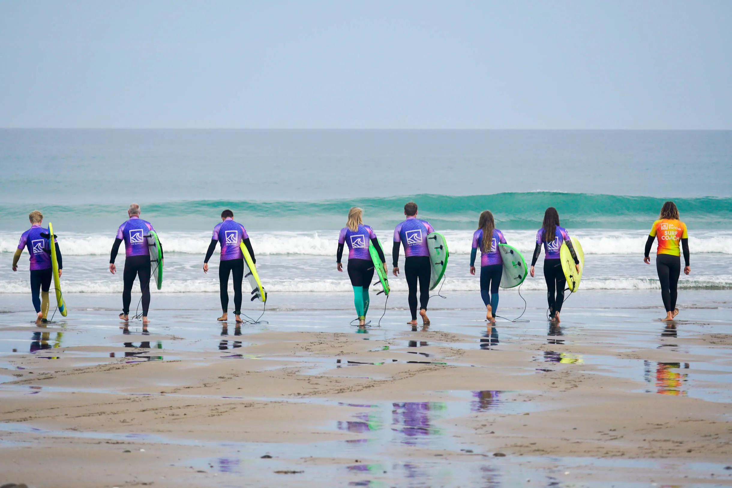 group surf lesson in Bude with OA Surf Club, surfers walking down the beach