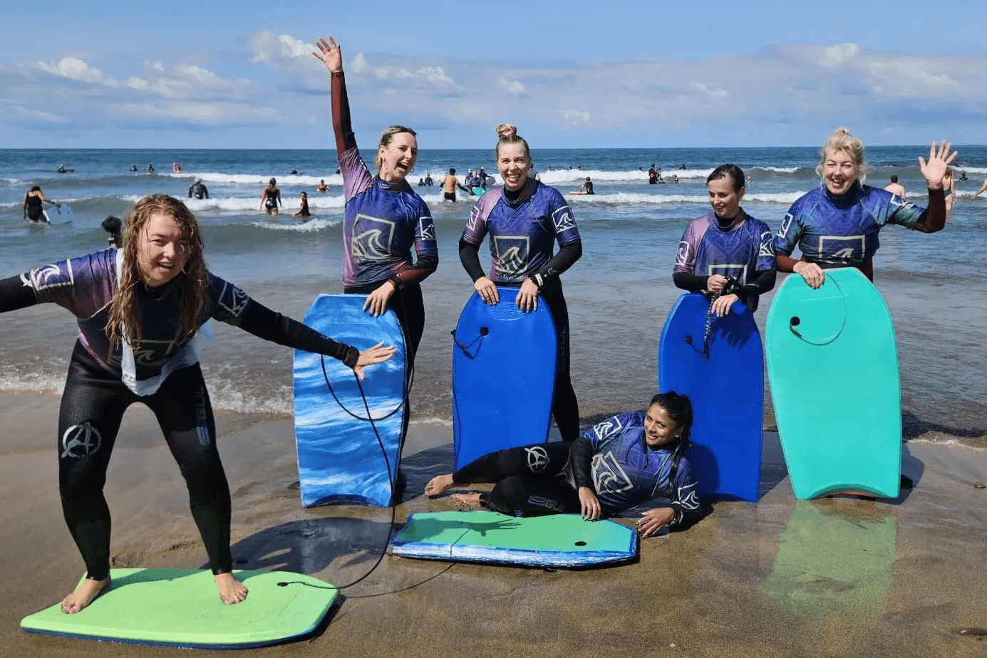 Group of ladies in wetsuits on the beach at widemouth bay with bodyboards